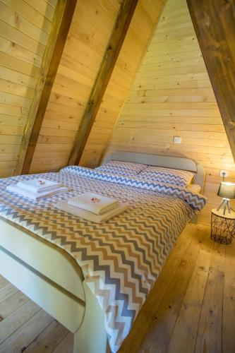 a bed in the attic of a wooden cabin at Mountain Houses Emilija in Žabljak