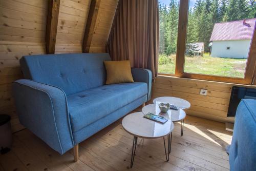 a living room with a blue couch and two tables at Mountain Houses Emilija in Žabljak