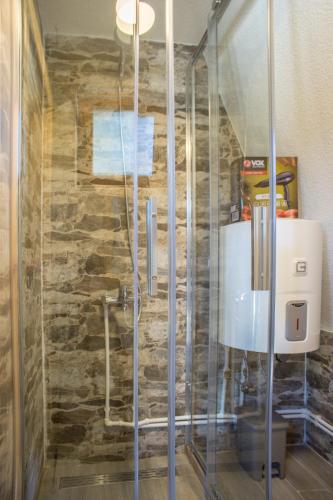 a shower in a bathroom with a stone wall at Mountain Houses Emilija in Žabljak