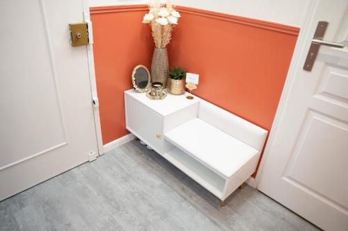a white cabinet in a hallway with an orange wall at 2-Bed Apartment - Sleeps 4 AirCon & Central Links in Le Kremlin-Bicêtre