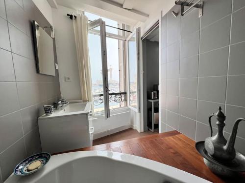 une salle de bain avec un lavabo et une grande fenêtre dans l'établissement Unique appartement Vieux Port, à La Ciotat