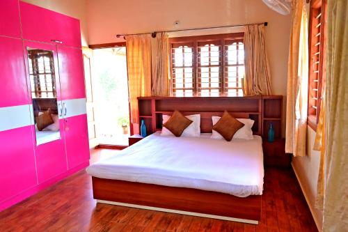 a bedroom with a large bed with pink walls at Hulihara Homestay - Full Villa, Coffee Estate & Balcony View in Sakleshpur