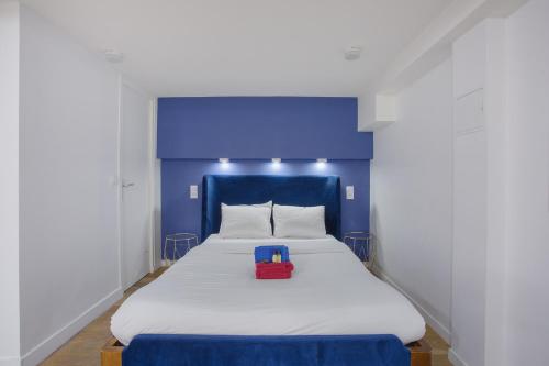 Una cama con una cabecera azul con una caja roja encima. en Rent a Room - 2P Passage du Caire, en París