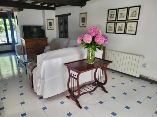 um vaso de flores cor-de-rosa numa mesa numa sala de estar em Casa Rural El Amparuco em Treceño