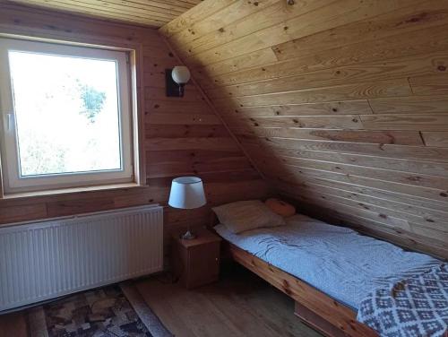 1 cama en una cabaña de madera con ventana en Bajkowy Domek nad rzeką Liwiec en Łochów