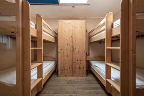a room with three bunk beds and a door at Vitalpina Hotel Waldhof in Rablà