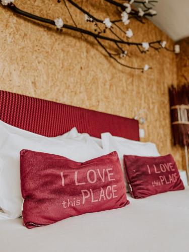 a bed with red and white pillows with i love this place at Natura Glamping in Alcongosta