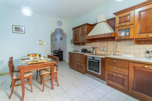 a kitchen with wooden cabinets and a table with chairs at Well Located Townhouse & Courtyard Kalka - Happy Rentals in Kalkara