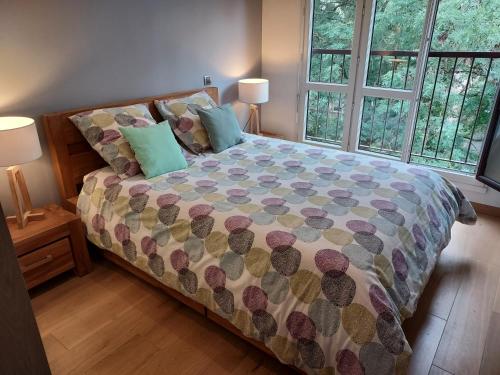 1 dormitorio con 1 cama con edredón y 2 ventanas en LES JARDINS D'ATILLY en Villecresnes
