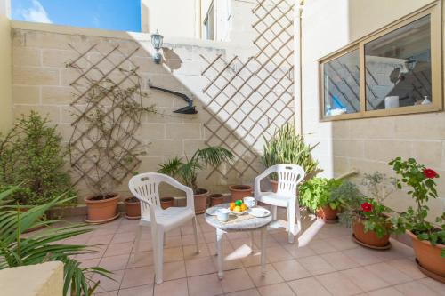 - 2 chaises et une table sur une terrasse agrémentée de plantes dans l'établissement Well Located Townhouse & Courtyard Kalka - Happy Rentals, à Kalkara
