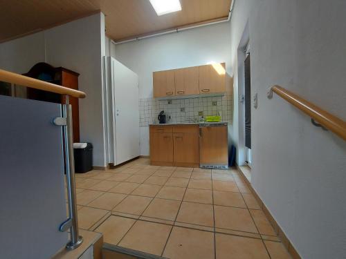 a kitchen with wooden cabinets and a tiled floor at Pension Hochheimer Schlösschen in Erfurt