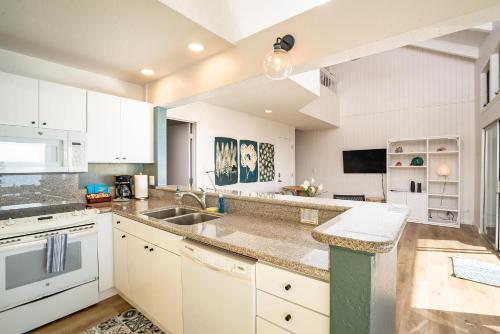 a kitchen with white cabinets and a sink at Pali Ke Kua #204 in Princeville