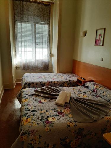 a bedroom with two beds and a window at Alojamento Local Pensão Rossio in Lisbon