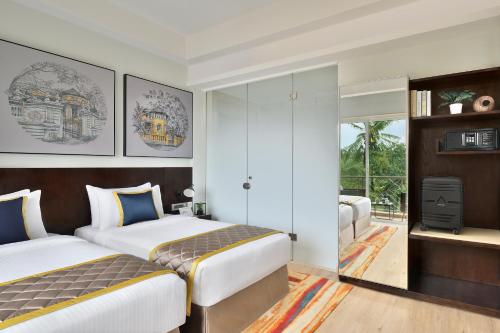 a hotel room with two beds and a television at Citadines Arpora Nagoa Goa in Arpora