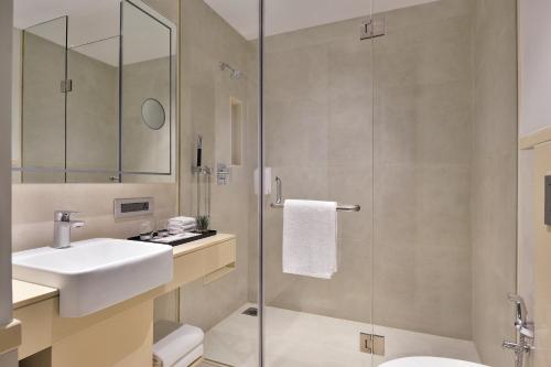 a bathroom with a sink and a glass shower at Citadines Arpora Nagoa Goa in Arpora