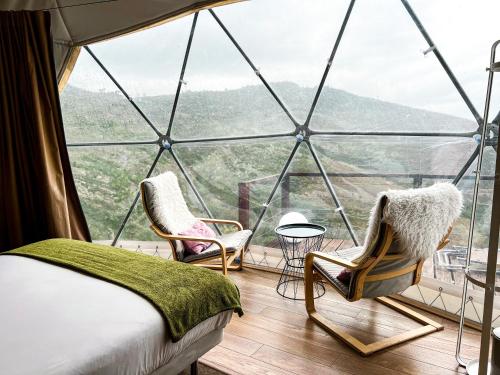 a room with two chairs and a bed in a glass house at Natura Glamping in Alcongosta