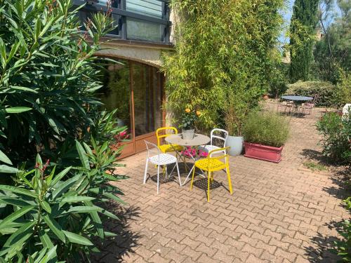 une terrasse avec une table, des chaises et des plantes dans l'établissement Le gîte des Tourterelles, à Belleville-sur-Saône