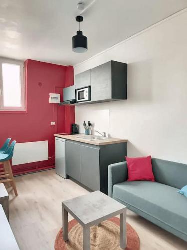 uma sala de estar com um sofá azul e uma cozinha em Stud' extra Cosy 2 pers gare wifi em Saint-Quentin
