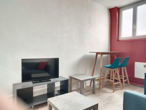 uma sala de estar com uma televisão de ecrã plano e cadeiras em Stud' extra Cosy 2 pers gare wifi em Saint-Quentin