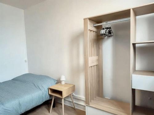 um quarto com uma cama e uma pequena mesa de cabeceira em Stud' extra Cosy 2 pers gare wifi em Saint-Quentin
