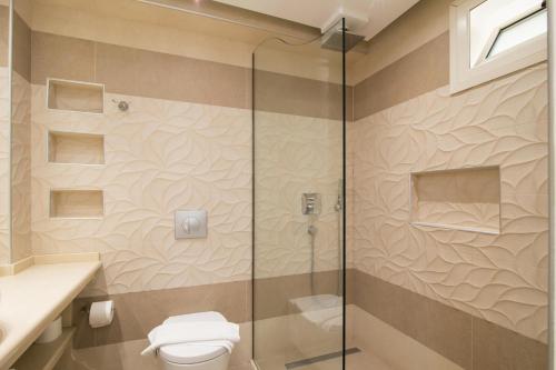 a bathroom with a toilet and a glass shower at Agios Gordios Beach Resort in Agios Gordios