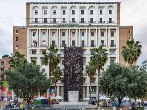 a large white building with palm trees in front of it at Boutique Hotel Piazza Carità in Naples
