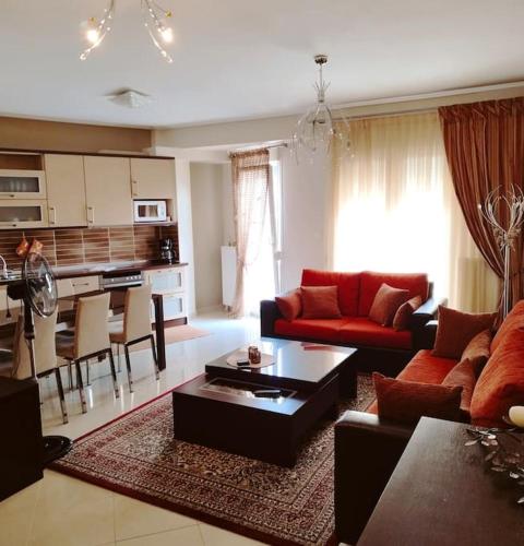 sala de estar con sofá rojo y cocina en Evaggelia's Apartments 5 Οικογενειακό Διαμέρισμα, en Kozani