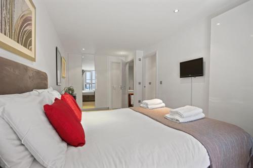 a bedroom with a large white bed with red pillows at Cubo Farringdon in London