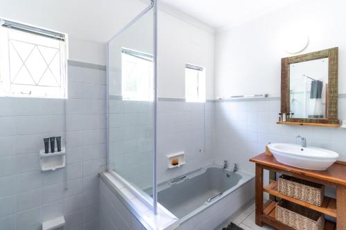Un baño con bañera, lavabo y espejo. en Wilderness Holiday Home - Riverside, en Wilderness