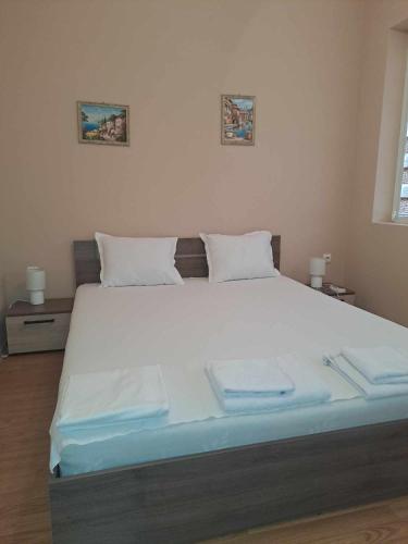 1 dormitorio con 1 cama grande con sábanas y almohadas blancas en АПАРТАМЕНТ Амира 2 en Balchik