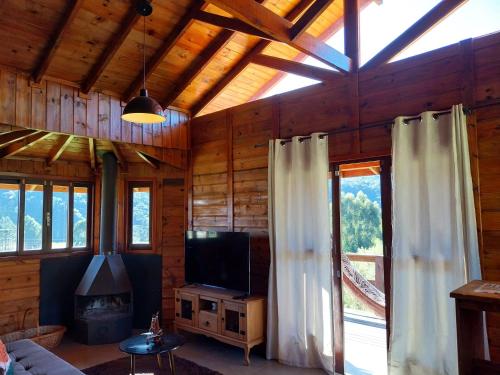 sala de estar con TV y ventana grande en Cabanas rota da neve, en Urubici