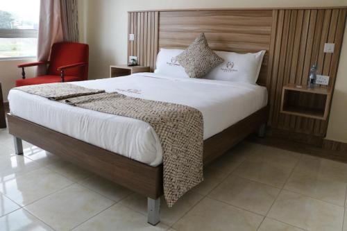 a bedroom with a large bed with a red chair at Paraiso Gardens Hotel in Wote