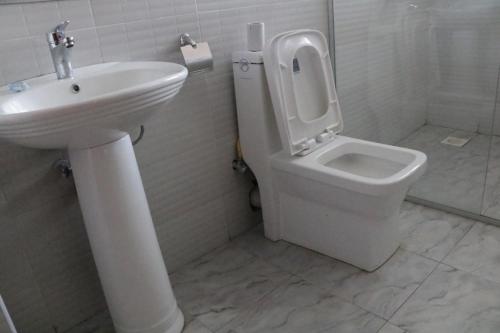 a white bathroom with a toilet and a sink at Paraiso Gardens Hotel in Wote