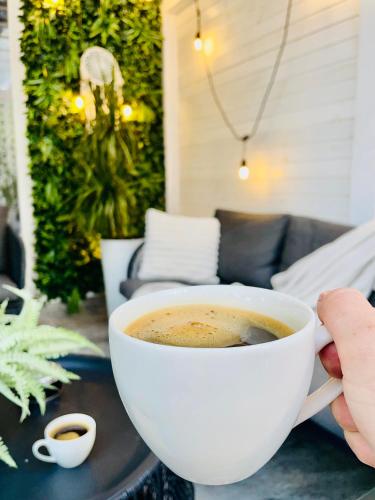a person holding a cup of coffee on a table at Aici te simți ca acasa 2 in Iaşi