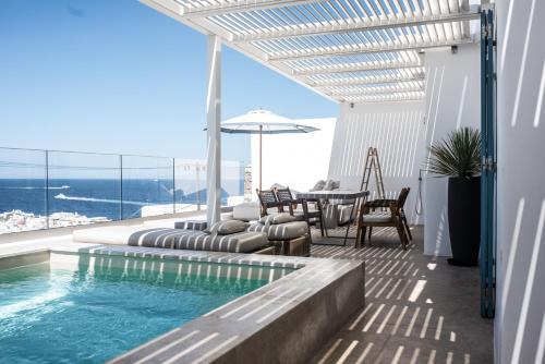 a patio with a swimming pool and a table and chairs at Νumi Boutique Hotel in Mikonos