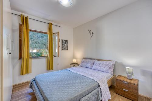 a bedroom with a bed and a window with yellow curtains at Holiday Apartment Stojanovski in Rovinjsko Selo