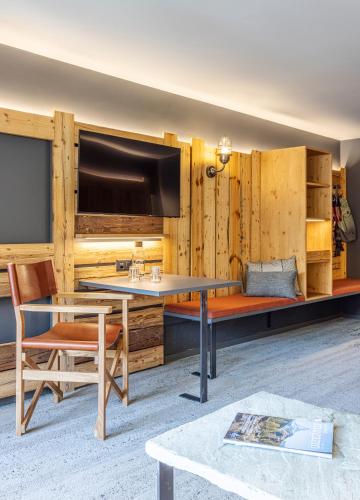 a living room with a table and a tv at BaseCamp Hotel in Zermatt