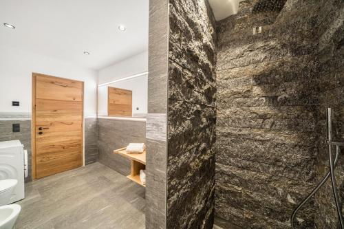 een badkamer met een stenen muur en een douche bij Waldes Duft Wohnung - Patleidhof in Naturno