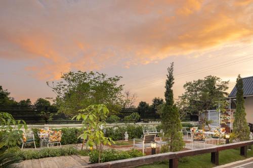 a garden with tables and chairs under a cloudy sky at Picha Ville Resort in Watthana Nakhon