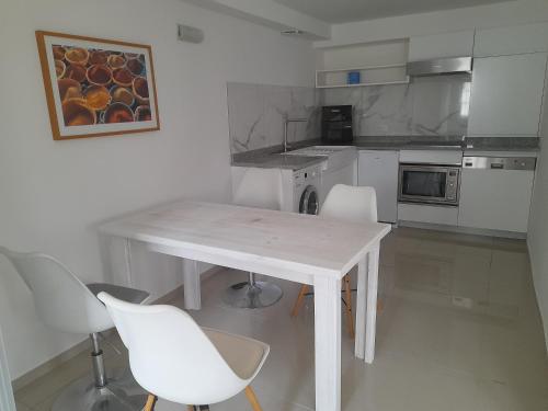 - une cuisine avec une table blanche et des chaises blanches dans l'établissement Appartement passion climatisé du Domaine d'Alzira, à Maisse