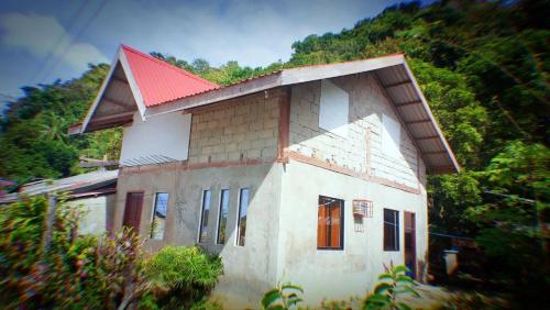 een klein huis met een rood dak op een berg bij YZRAJ Homestay in El Nido