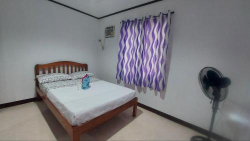 een kleine slaapkamer met een bed en een ventilator bij YZRAJ Homestay in El Nido