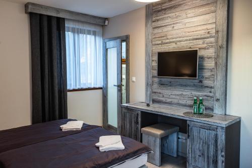 a bedroom with a bed and a desk with a television at Vila Ambiente Donovaly in Donovaly