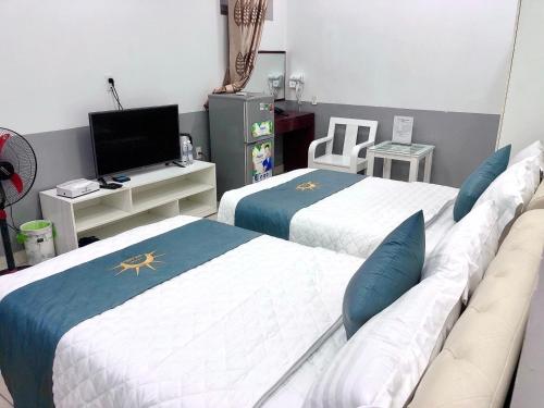 two beds in a room with a tv and a room at Holiday Hotel 2 in An Khê