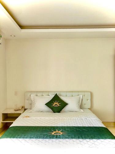 a bedroom with a white bed with a green pillow at Holiday Hotel 2 in An Khê
