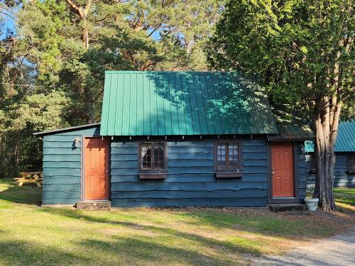 una casa azul con puertas rojas y techo verde en Moreno's Cottages en Saranac Lake