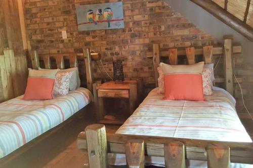 two beds in a room with wooden walls at Kudu's Rus in Marloth Park in Marloth Park