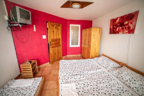 two beds in a room with a red wall at Vinný sklep Kovárna in Rohatec