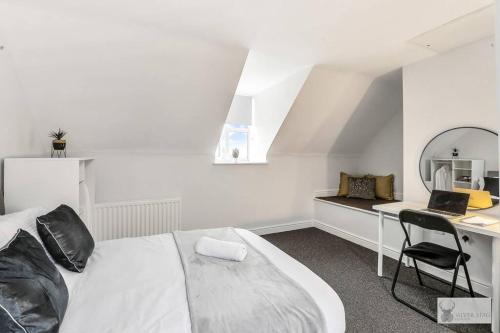 ein Schlafzimmer mit einem Bett und einem Schreibtisch mit einem Laptop in der Unterkunft Modern 4-Bedroom Gem Family & Business Friendly in Coalville
