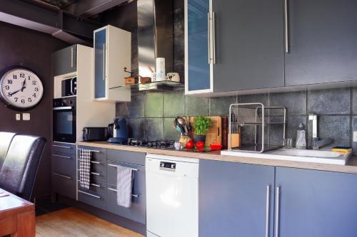 une cuisine avec des placards bleus et une horloge murale dans l'établissement Dolce Vita - Jacuzzi - La Ciotat, à La Ciotat